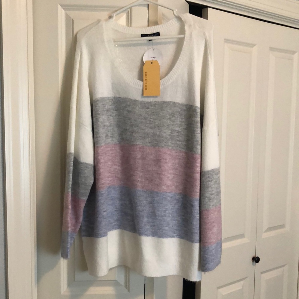White sweater with blue, maroon, and grey stripe.
